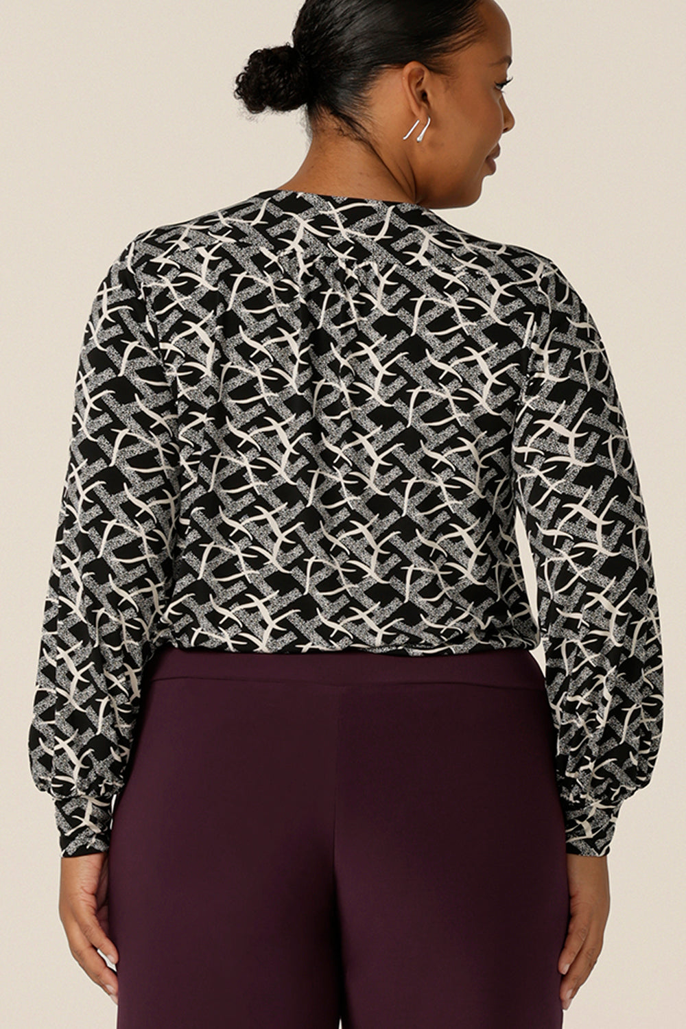 Back view of a size 18, plus size woman wears a long sleeve top with bishop sleeve cuffs and a scoop neck in black and white print jersey. Made in Australia by Australian and New Zealand women's clothing brand, L&F this women's work top is available to shop in sizes 8 to 24.