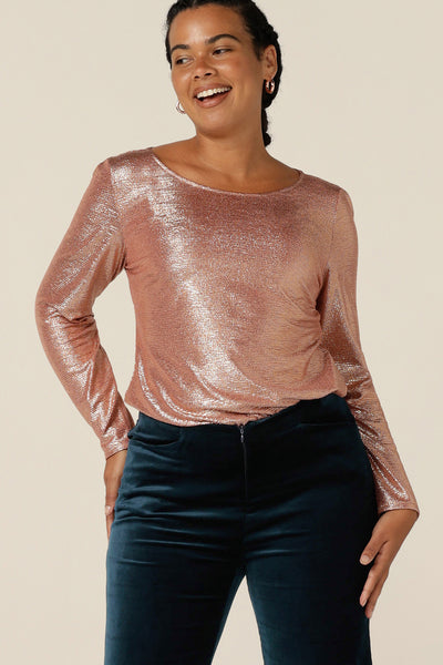 A size 12 woman wears a shimmering pink sparkly top with high scoop neck and long sleeves. Simple and easy-to-wear, this comfortable evening top is made in Australia in sizes 8 to 24. 