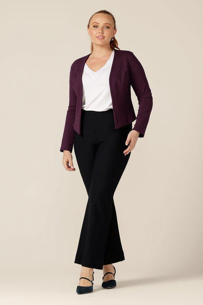 A good workwear jacket, the Mackenzie Jacket in Mulberry by Australian and New Zealand womenswear brand, L&F is a collarless, open front jacket with long sleeves and an angled hem. Worn with a white bamboo jersey top and boot cut, flared leg navy trousers.