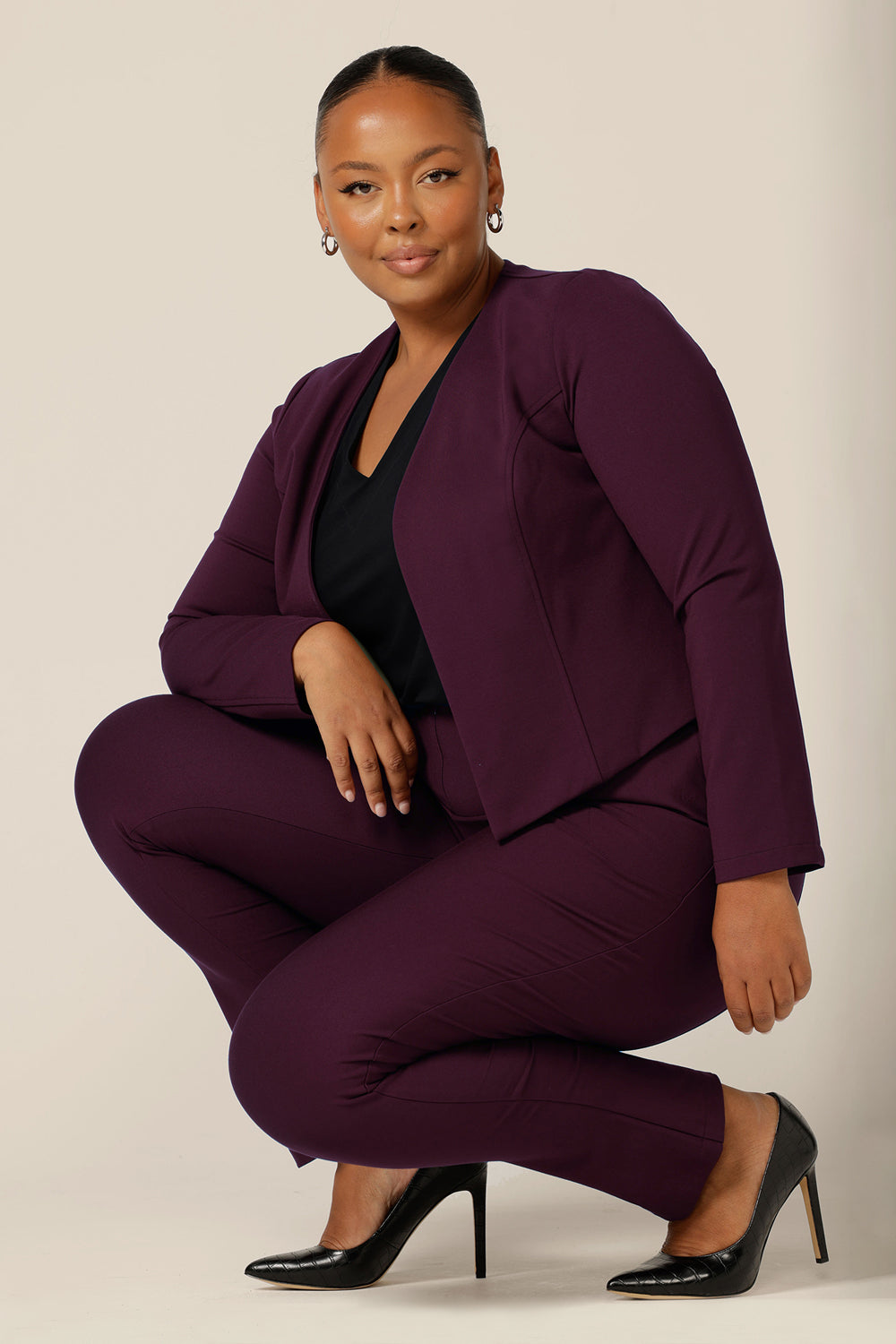 A good workwear jacket for plus size women, the Mackenzie Jacket in Mulberry is available to shop in sizes 8 to 24. Made in Australia by Australian and New Zealand womenswear brand, L&F, this work jacket is a collarless and open fronted with long sleeves and an angled hem. This corporate jacket is worn with slim leg pants and a black, V-neck top.
