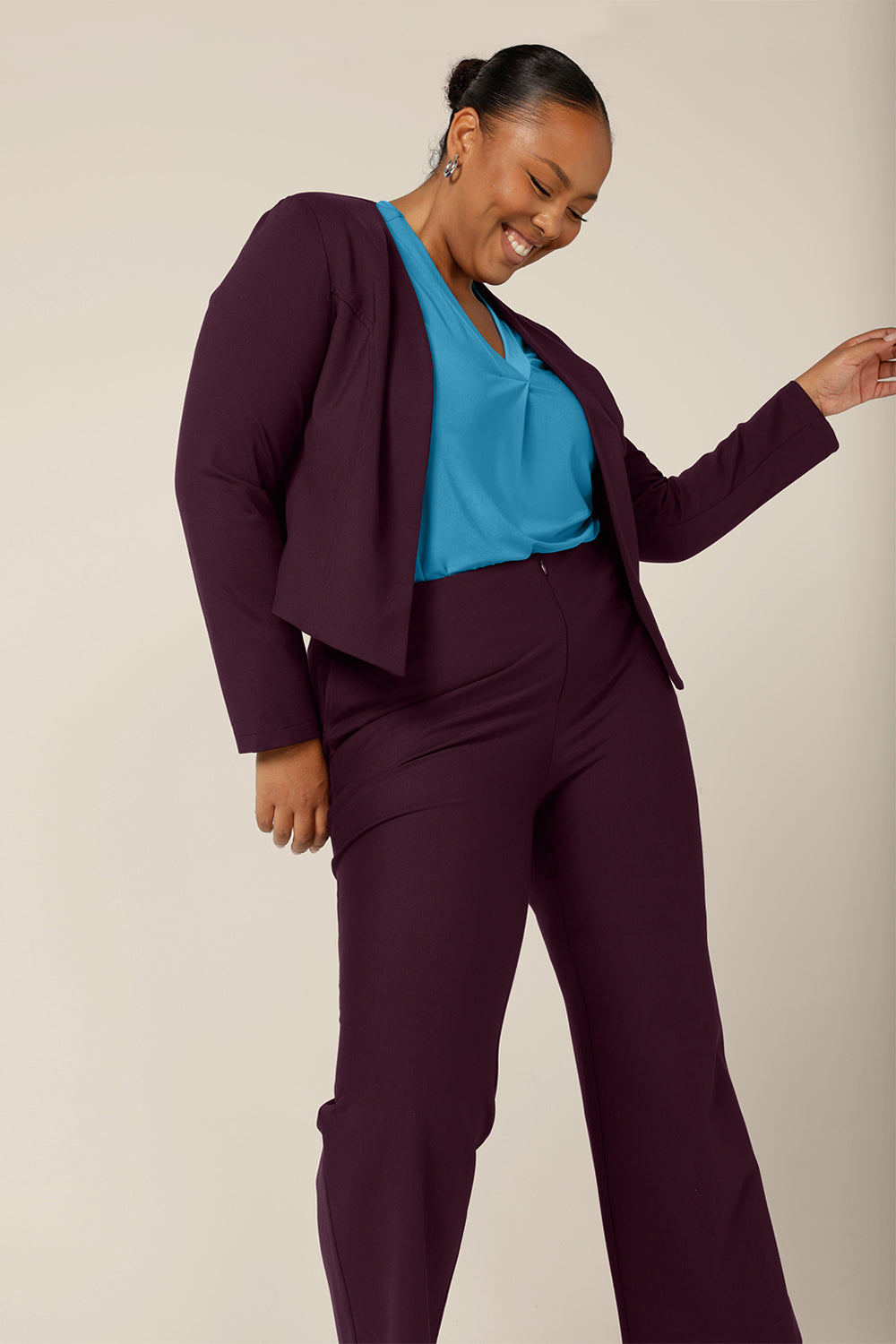 A good work jacket for plus size women, the Mackenzie Jacket in Mulberry is available to shop in sizes 8 to 24. Made in Australia by Australian and New Zealand womenswear brand, L&F, this work jacket is a collarless and open fronted with long sleeves and an angled hem. This corporate jacket is worn with slim leg pants and a V-neck top in opal blue..