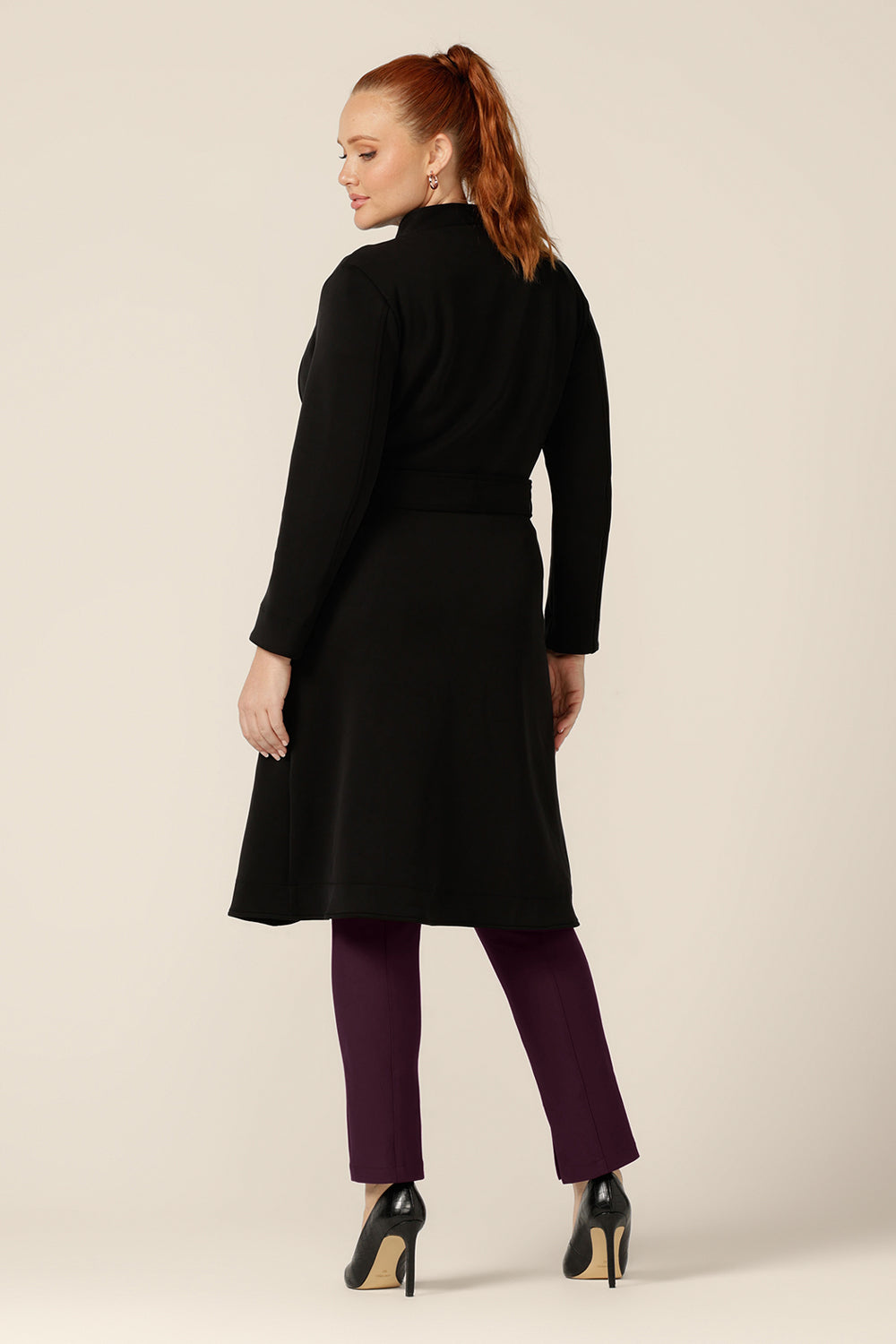 Great for chic city style, this black coat layers well for commuter workwear and travel. Shown as a back view and worn tied at the waist, this softly tailored black trenchcoat in modal fabric is made in Australia by Australian and New Zealand women's clothing label, L&F.
