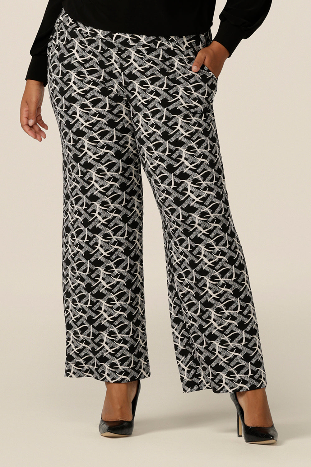 A plus size, size 18 woman wears wide leg, pull on pants with a deep waistband in black and white jersey. Australian-made, these easy care pants are great for work and corporate wear.