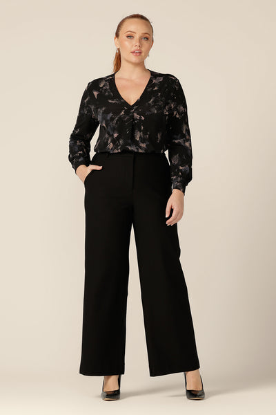 A size 12 woman wearing a long sleeve, V-neck top in printed black jersey with tailored, blackwork pants. Made in Australia by Australian and New Zealand women's fashion brand, L&F, this comfortable top is good for work and casual wear.