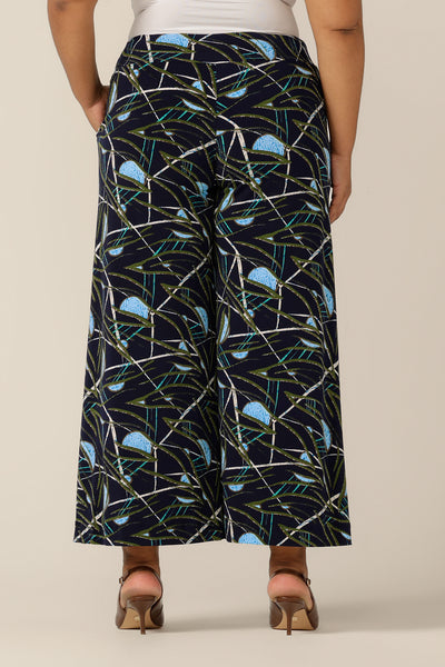 Back view of Australian-made wide-leg pants in a size 18 by Australian and New Zealand women's clothing brand, L&F. Featuring a blue, green and white abstract print on navy-base jersey, these stretch-fit wide leg trousers wear well for work wear or casual wear. Shop trousers in petite to plus sizes now.