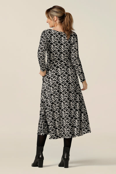 Back view of a size 12, curvy woman wearing a midi length, long sleeve dress with twisted keyhole detail. A dress for work or weekend wear, this elegant dress is made by Australian and New Zealand women's clothing label, L&F in an inclusive size range of sizes 8 to 24.