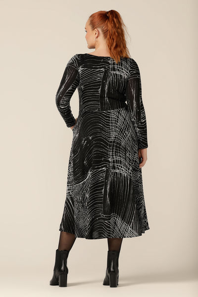 Back view of a size 12, curvy woman wearing a midi length, long sleeve dress with twisted keyhole detail. A dress for work or weekend wear, this knit dress is made by Australian and New Zealand women's clothing label, L&F in an inclusive size range of sizes 8 to 24.