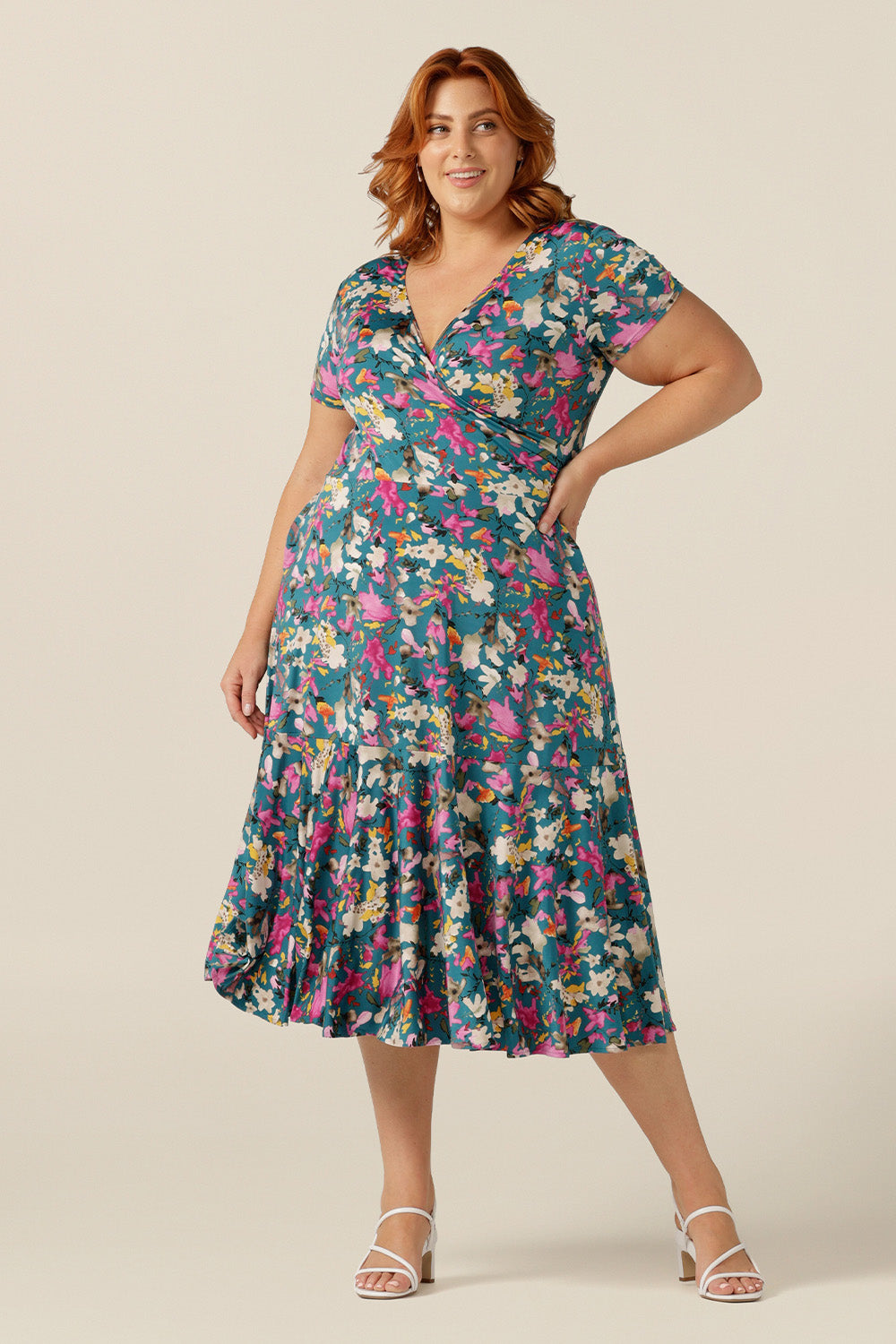 A plus size woman wearing a fixed wrap jersey dress with short sleeves and a floral print. The dress features a maxi-length skirt with pockets. Made in Australia by women's clothing brand L&F, this wrap dress fits petite to curvy women.