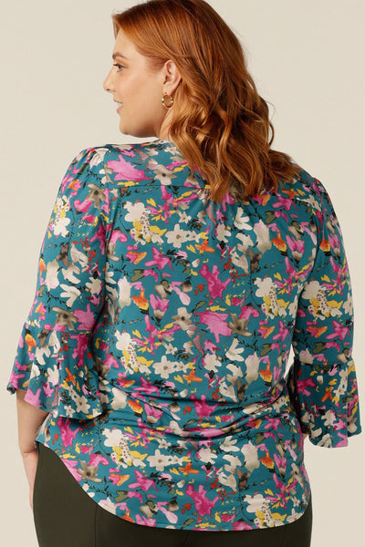 a size 18 curvy woman wearing a semi-fitted jersey top. The top features 3/4 sleeves with fluted cuffs, a V-neck and  a floral print. The top was made in Australia in petite to plus sizes by women's clothing brand, Leina and Fleur