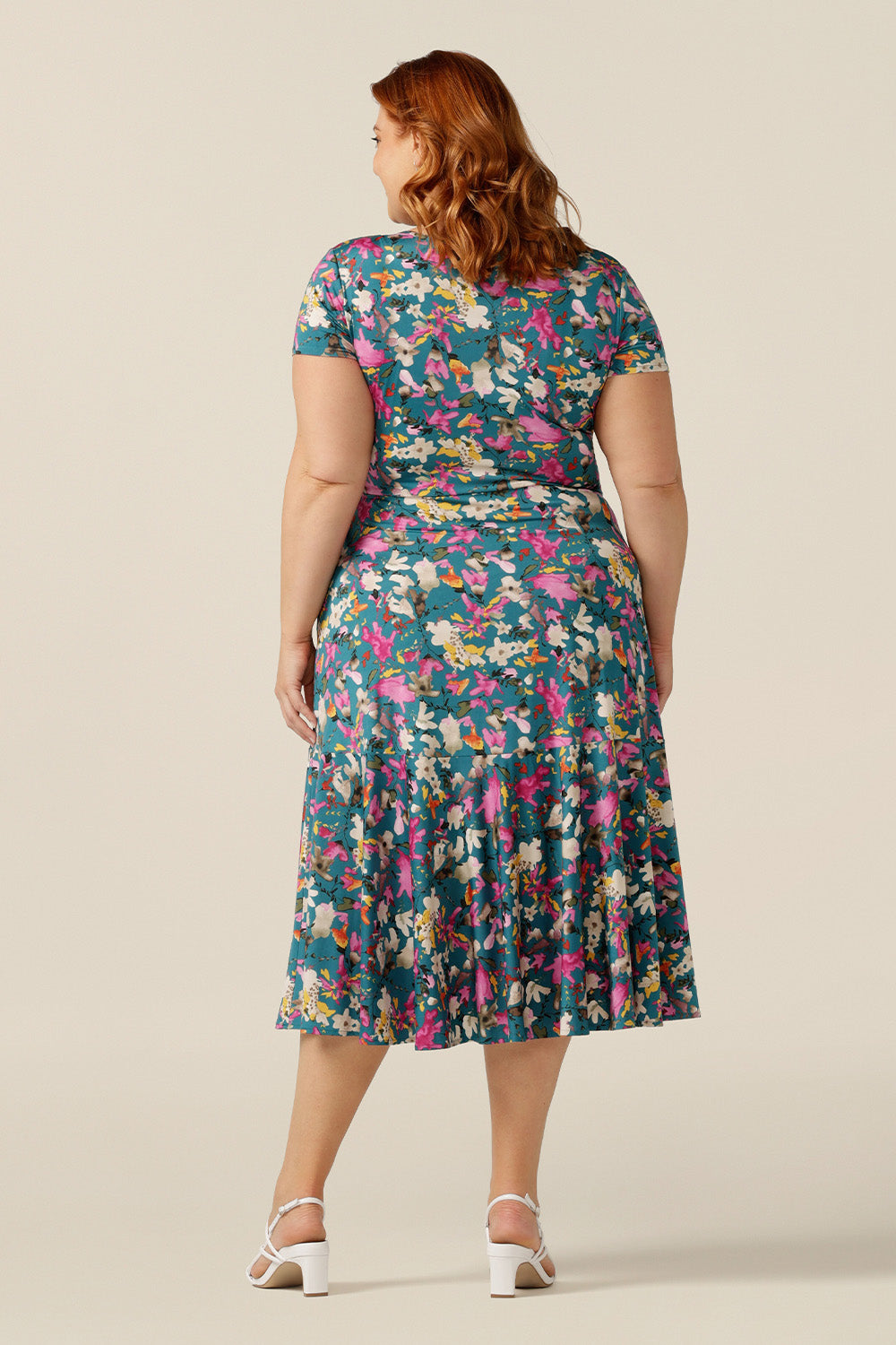A plus size woman wearing a fixed wrap jersey dress with short sleeves and a floral print. The dress features a maxi-length skirt with pockets. Made in Australia by women's clothing brand L&F, this wrap dress fits petite to curvy women.