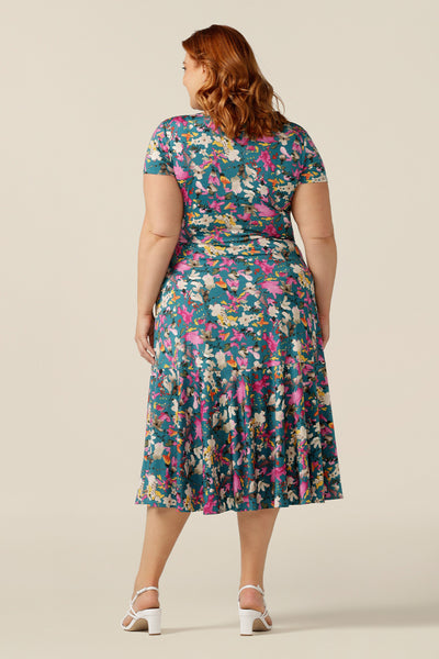 A plus size woman wearing a fixed wrap jersey dress with short sleeves and a floral print. The dress features a maxi-length skirt with pockets. Made in Australia by women's clothing brand L&F, this wrap dress fits petite to curvy women.