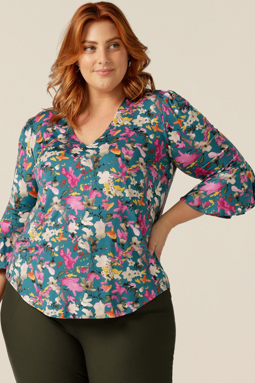 a size 18 curvy woman wearing a semi-fitted jersey top. The top features 3/4 sleeves with fluted cuffs, a V-neck and  a floral print. The top was made in Australia in petite to plus sizes by women's clothing brand, Leina and Fleura size 18 curvy woman wearing a semi-fitted jersey top. The top features 3/4 sleeves with fluted cuffs, a V-neck and  a floral print. The top was made in Australia in petite to plus sizes by women's clothing brand, Leina and Fleur