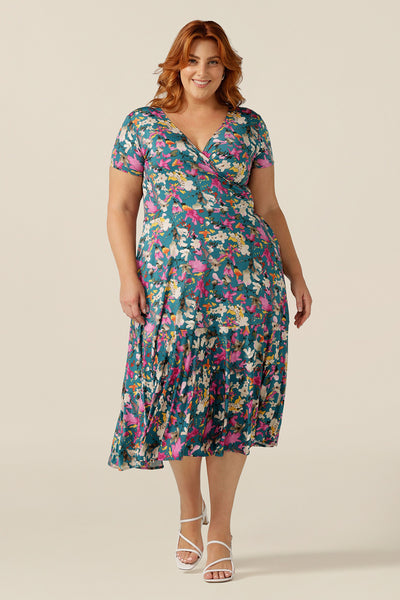 A plus size woman wearing a fixed wrap jersey dress with short sleeves and a floral print. The dress features a maxi-length skirt with pockets. Made in Australia by women's clothing brand L&F, this wrap dress fits petite to curvy women.