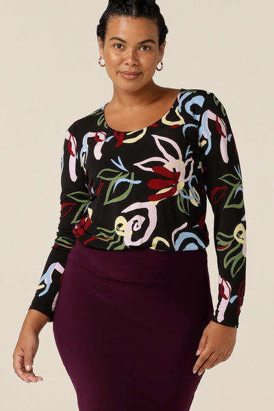 Styled for work, a round neck jersey top with abstract print and full length sleeves is worn tucked in to a workwear tube skirt in Mulberry.