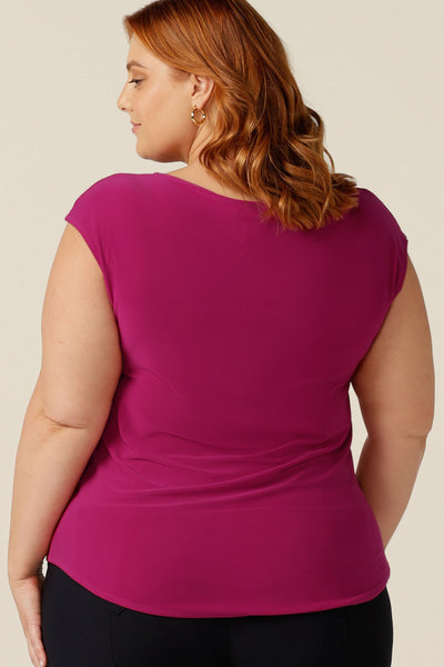 A back view of a plus size, size 18 woman wearing a cap-sleeve top with a boat neckline. Available in fuchsia pink jersey, the Aspen Top gives colour to corporate wear and makes a good work wear top.