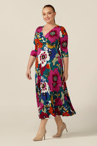 A size 12, curvy woman wears a 3/4 sleeve, fixed wrap dress in floral print jersey. Made in Australia by  Australian and New Zealand fashion brand, L&F this jersey wrap dress is reversible and can be worn with a boat neckline. A maxi dress for work or occasion wear, shop now in sizes 8-24.