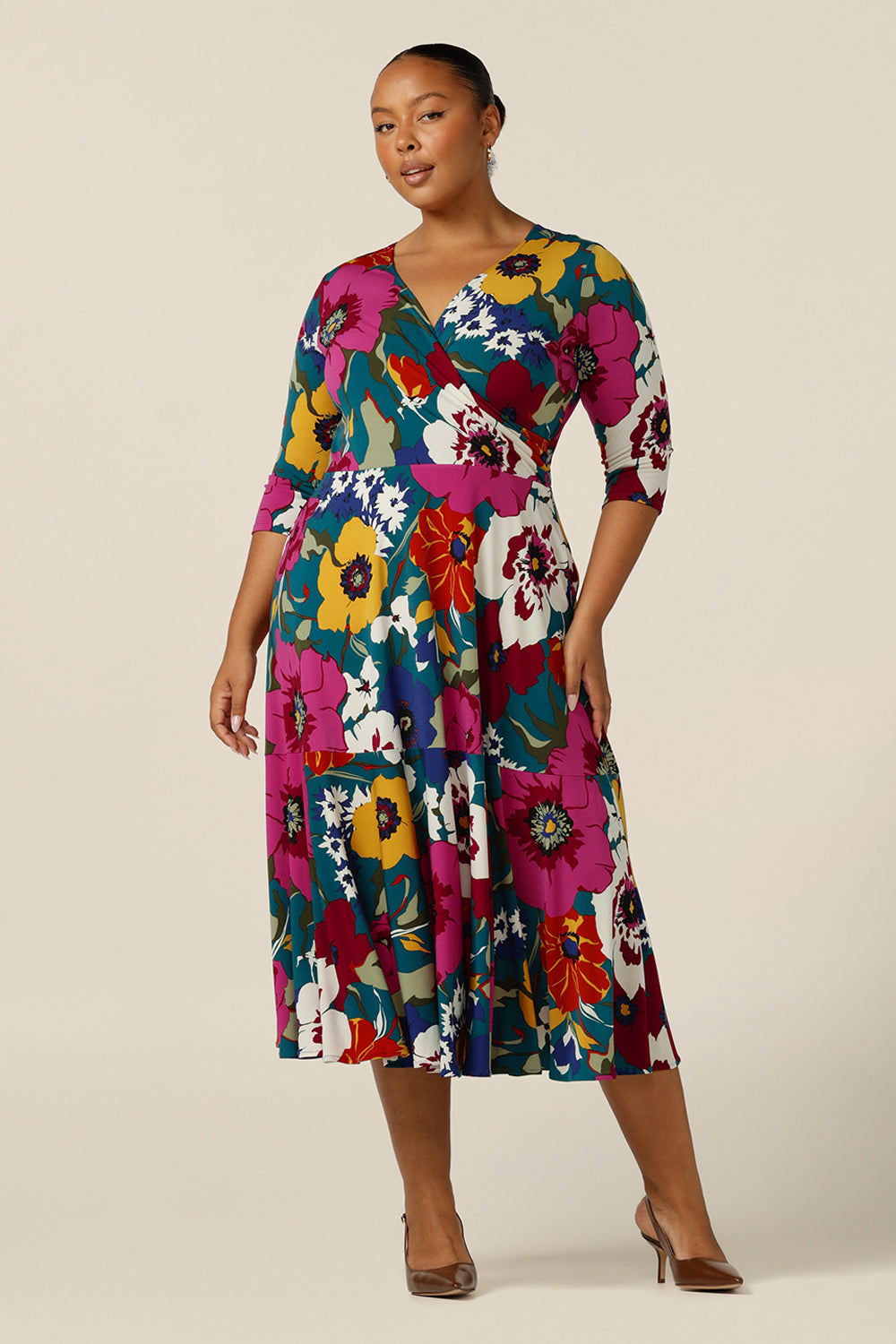 A size 18, plus size woman wears a fixed wrap dress in printed jersey. Made in Australia by  Australian and New Zealand fashion brand, L&F this jersey wrap dress is reversible and can be worn with a boat neckline. A dress for work or occasion wear, shop now in sizes 8-24.