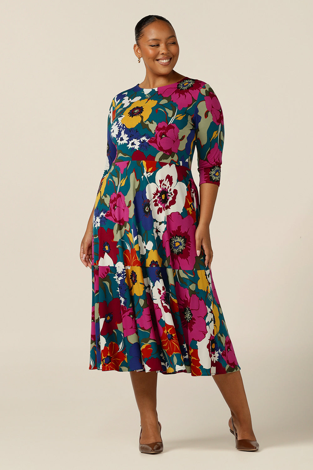 A size 18, plus size woman wears a reversible wrap dress in printed jersey. Made in Australia by Australian and New Zealand fashion brand, L&F this 3/4 sleeve jersey dress is worn with a boat neckline but reverse it and it becomes a wrap dress! A dress for corporate or occasion wear, shop your next event dress now in sizes 8-24.