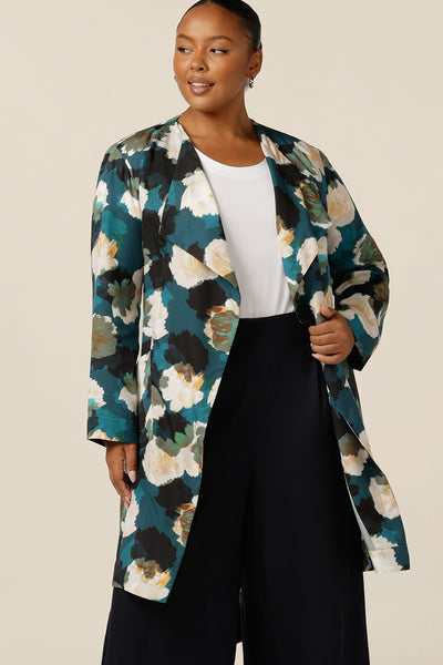 a size 18, curvy woman wears the best jacket for autumn/winter 2023. In sustainable Tencel fabric, this jacket's floral print (designed exclusively for Australian-made women's clothing company L&F) is on a teal base with white and navy flowers. A luxury jacket, shop it in plus sizes for fuller figure online at leina and fleur. 