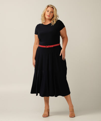 A black dress is paired with a petite red leatherette belt with a silver buckle, worn around the waist by a plus-size model.