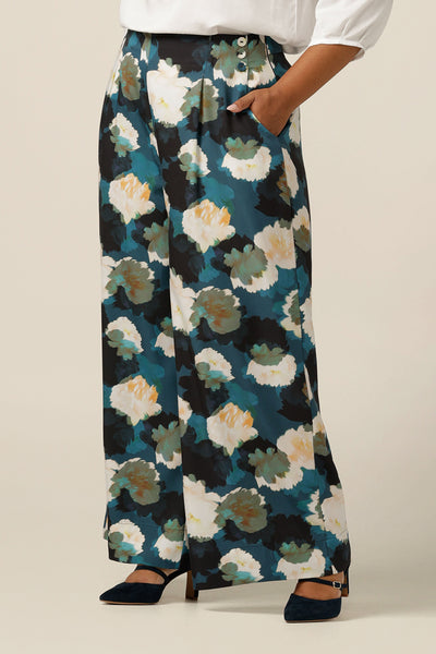 A size 18 woman wears high-waisted printed wide-leg pants. Made in Australia from sustainable Tencel fabric, these eco-conscious trousers are part of women's clothing brand, elarroyoenterprises's focus on size inclusive, sustainable fashion.