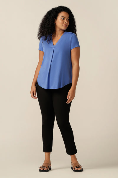 A curvy size 12 woman wears a blue bamboo jersey top. The top has short sleeves and a V-neckline. Worn with slim leg, cropped black trousers, this bamboo jersey top can be worn as a comfortable work wear top or as a casual top. Made in Australis and in natural, sustainable fibres, this bamboo jersey top is helping L&F work towards more sustainable and eco-conscious fashion. 