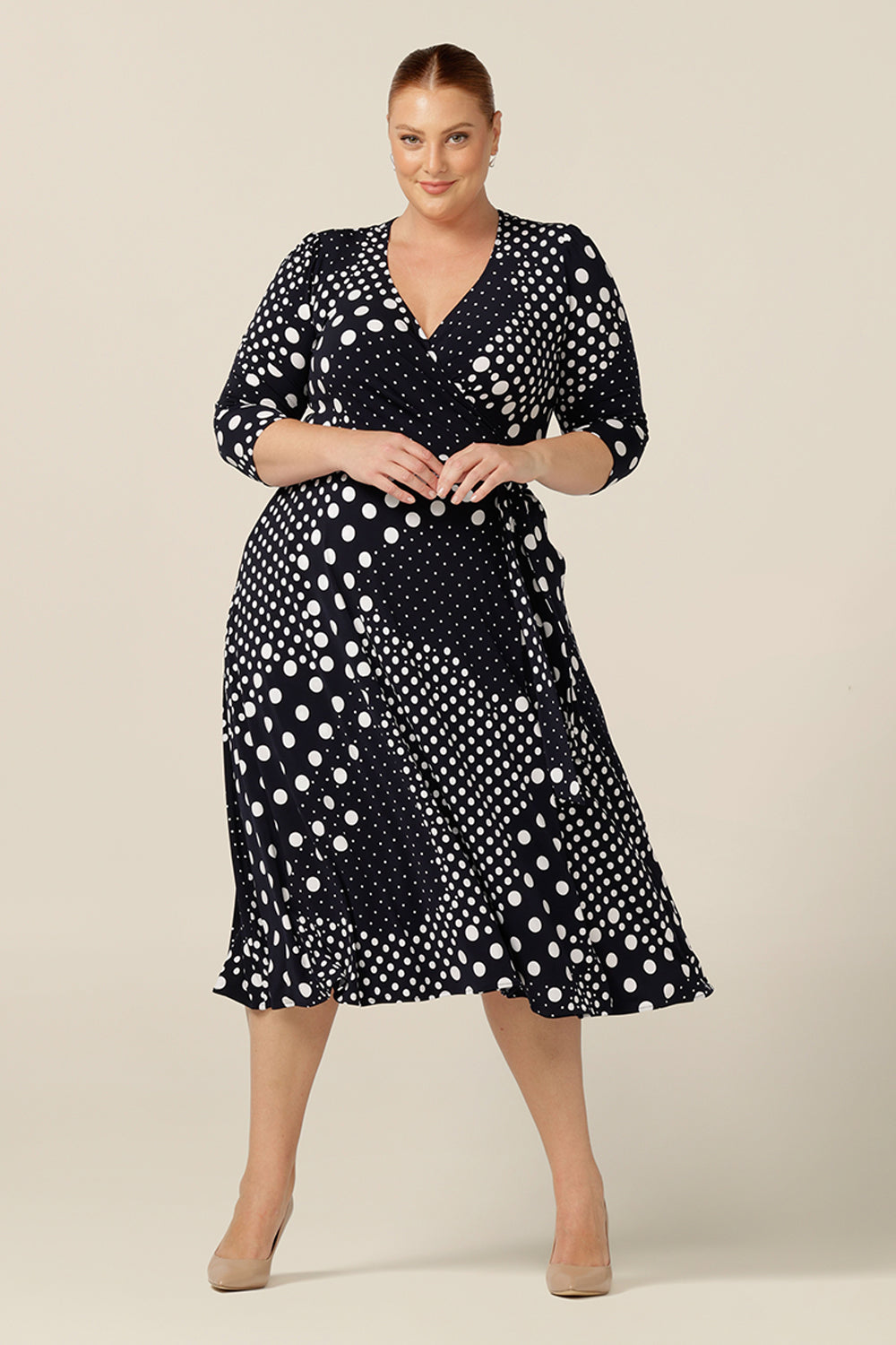 Made in Australia, this jersey wrap dress with navy and white polka dot print, is a great workwear and occasion dress. Featuring 3/4 sleeves and a full, below-the-knee length skirt, this wrap dress is available to shop online in sizes 8 to plus sizes 18-24.
