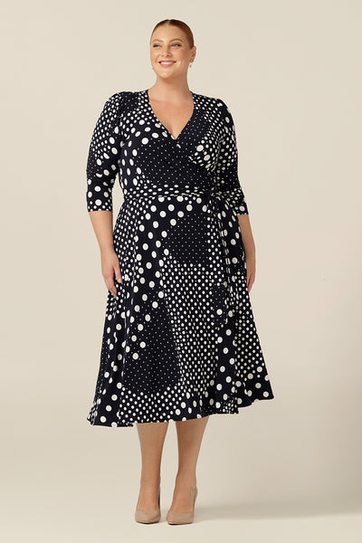 A jersey wrap dress with navy and white polka dot print, this is a great workwear dress. Featuring 3/4 sleeves and a full, below-the-knee length skirt, this wrap dress looks stylish on plus size and fuller figure women.