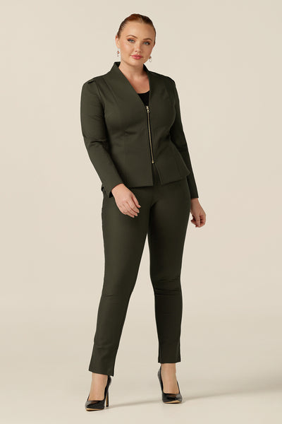 A size 12, curvy woman wears a tailored jacket with collarless V-neckline and zip fastening. In olive green ponte jersey, the stretch fabric makes for a comfortable workwear jacket.