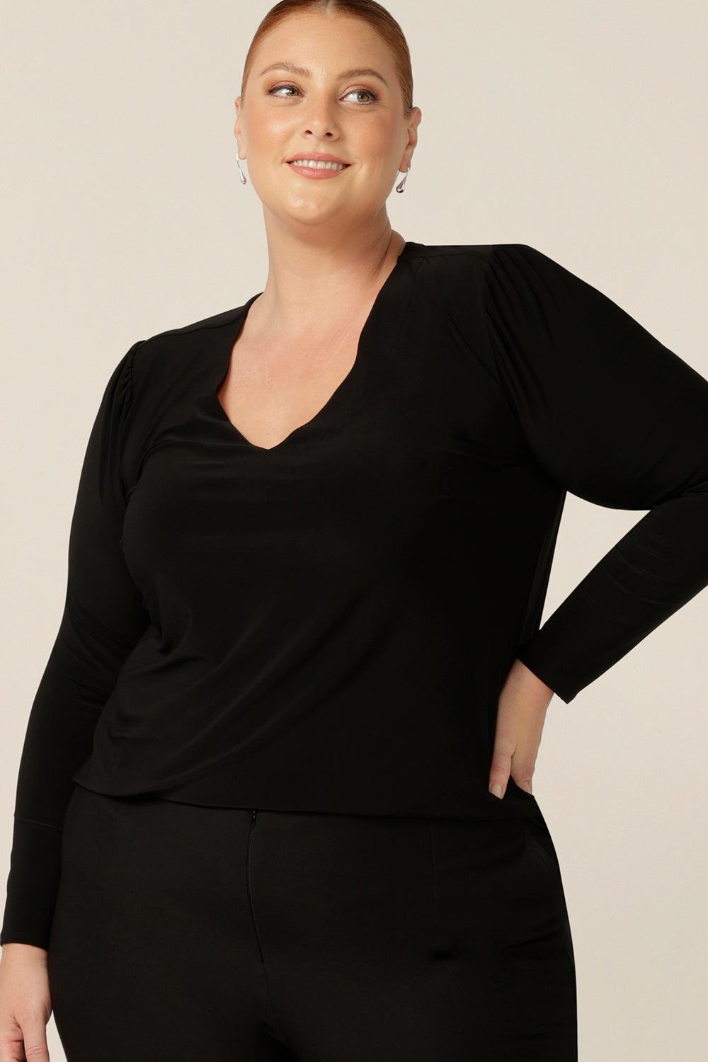 A size 18, fuller figure woman wears a long sleeve, V neck top in black jersey. A comfortable top for work or casual wear, this classic women's top is made in Australia by Australia and New Zealand women's clothing label, L&F..