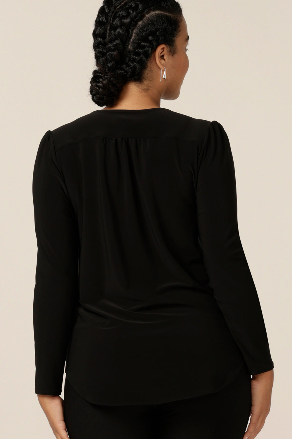 Back view of a size 12, curvy woman wearing a long sleeve, V neck top in black jersey. A comfortable top for work or casual wear, this classic black women's top is made in Australia by Australia and New Zealand women's fashion label, L&F.