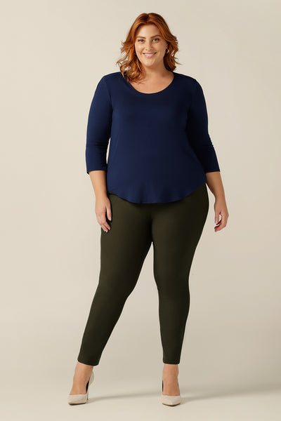 A plus size woman wears a navy blue top in bamboo jersey. The casual women's top has a round neck and 3/5 sleeves. In sustainable bamboo jersey, this top is lightweight and breathable. Worn with cropped olive green trousers, this top is styled for casual wear comfort.
