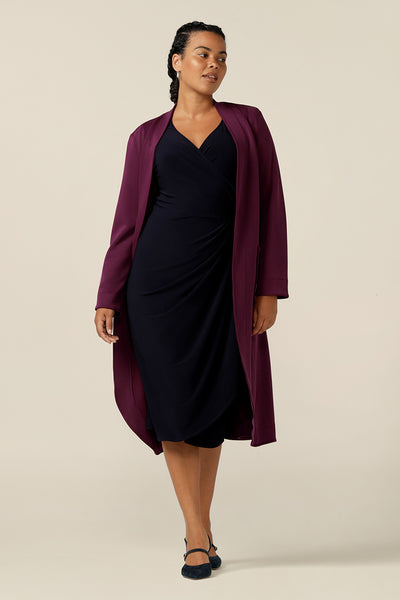 A size 12, curvy woman wears a soft tailoring trenchcoat by Australia and New Zealand women's fashion label, L&F. In wine red Modal fabric, this light-weight winter coat is comfortable for layering over workwear and corporate suiting for winter work wear solutions.