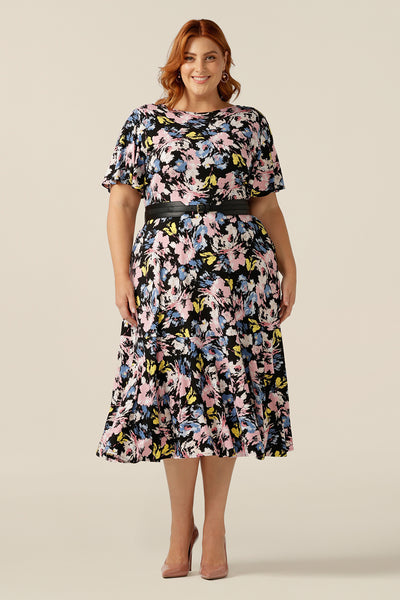 A vintage floral print dress, the Nicolle Reversible dress is worn by a size 18 woman. The dress is shown with a boat neckline but can be reversed and worn as a wrap front dress style. With short sleeves and a full skirt this dress is good for work wear and as an occasionwear dress. Available online in sizes 8 to sizes 24. 