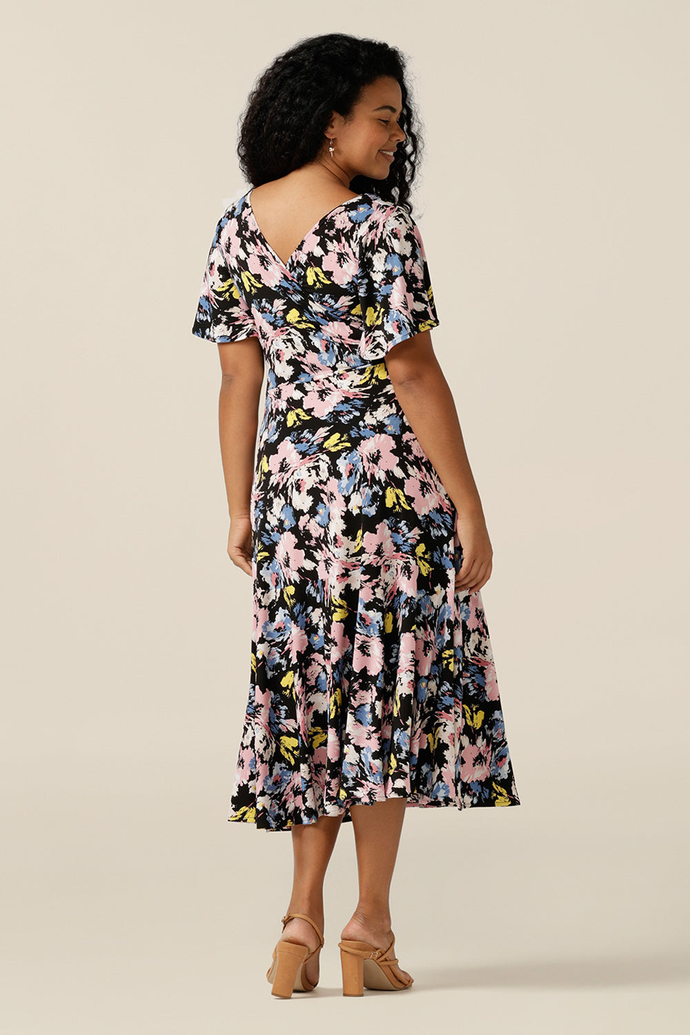 Vintage floral print dresses for women over 40, the Nicolle Reversible Dress is shown here on a size 12 curvy woman. A reversible style dress, she is worn here as wrap front with V-neckline but can worn with a boat neckline. A dress with arm coverage, it has short sleeves and a full midi-length skirt. A dress for feminine corporate dressing and work attire, this dress comes in sizes 8 to sizes 24.