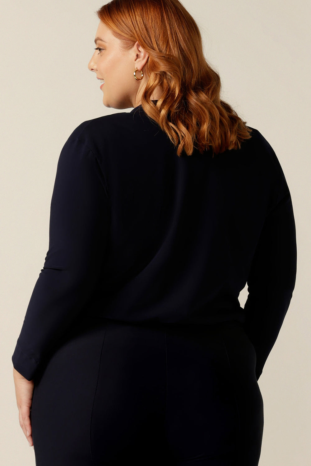 A plus size woman wears a soft navy jacket in a size 18. The best jacket for autumn/winter, this long sleeves 2-button cover-up is a as comfortable as a cardigan but with a corporate edge that transitions for work wear.