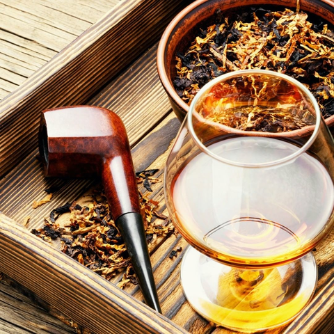 A pipe and some tobacco on a tray with a glass of cognac