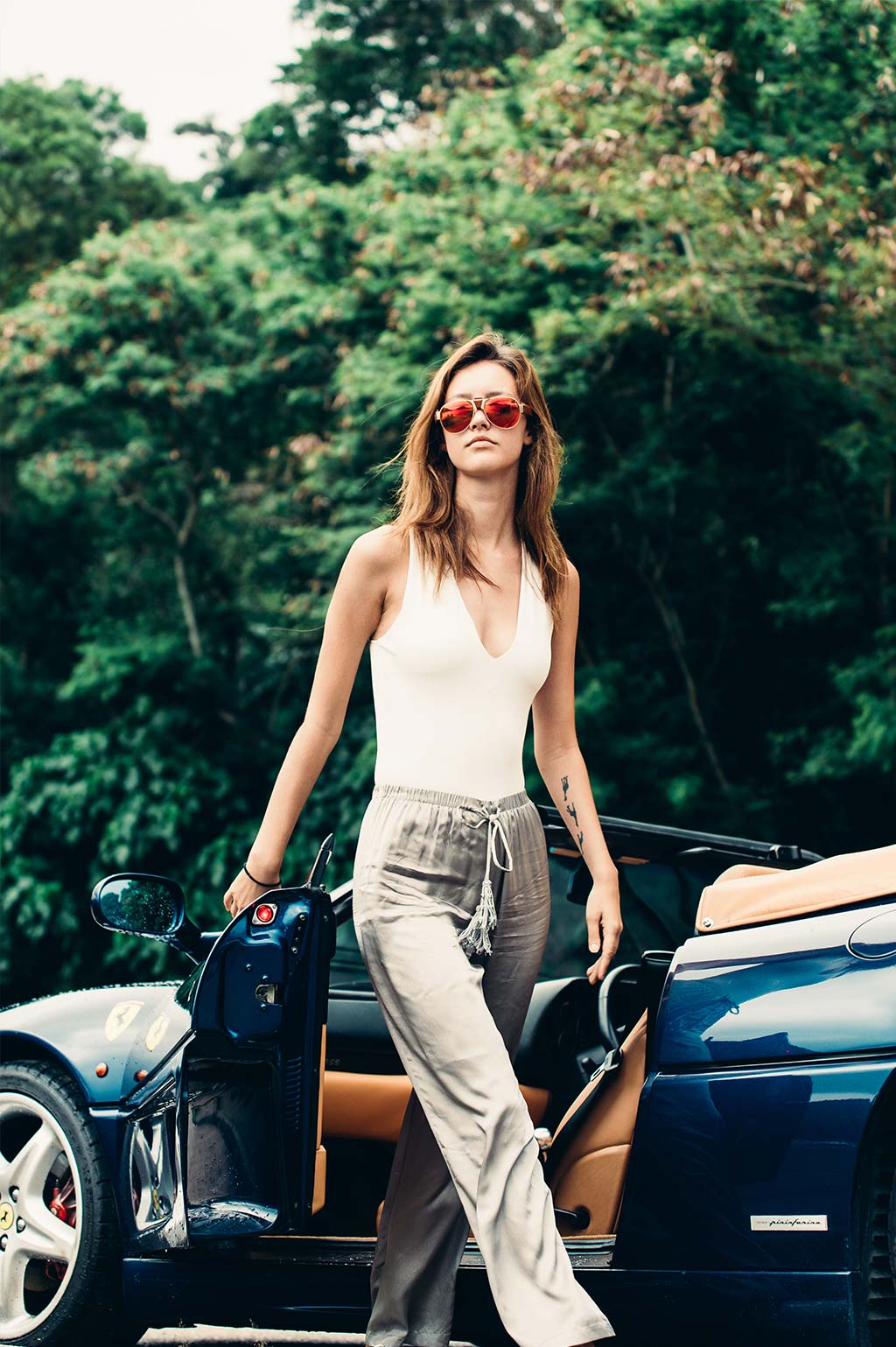 Female model wearing Baendit sunglasses next to a sports car