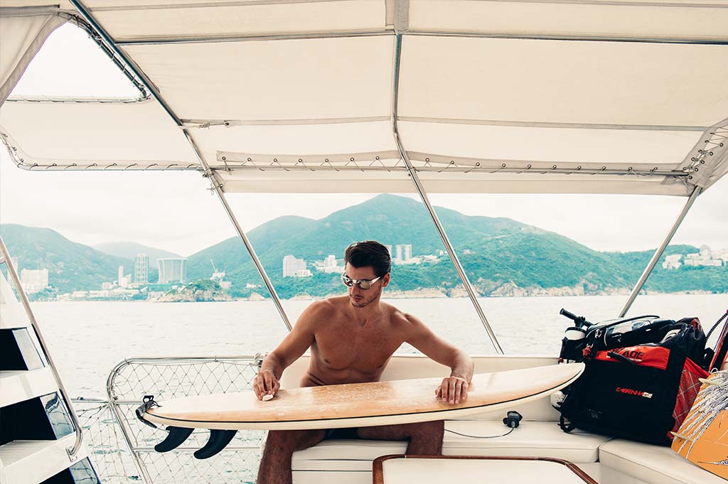 Male model wearing Baendit on a boat with surf board