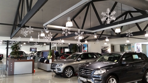 Christmas snow flake ornaments dangling from the roof of car showroom