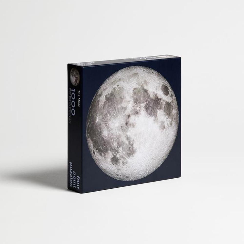 A partially assembled The Moon 1000-Piece Jigsaw Puzzle with some of its pieces scattered.