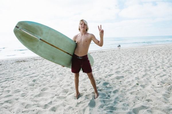 kid with surfboard giving peace sign