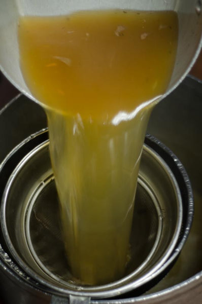 Bone broth being poured into a strainer.