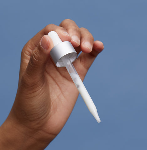 A hand holding a serum dropper