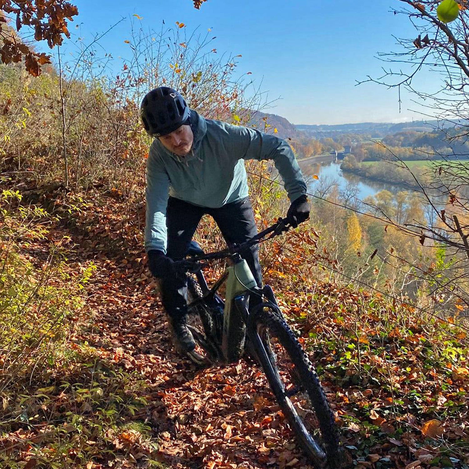 Mensch auf einem Fahrrad im Wald mit Laub auf dem Boden
