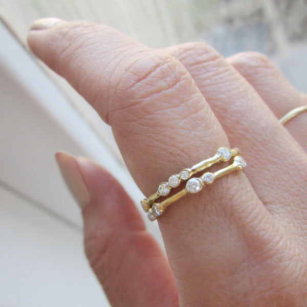 two yellow gold and diamond rings on model's hand 