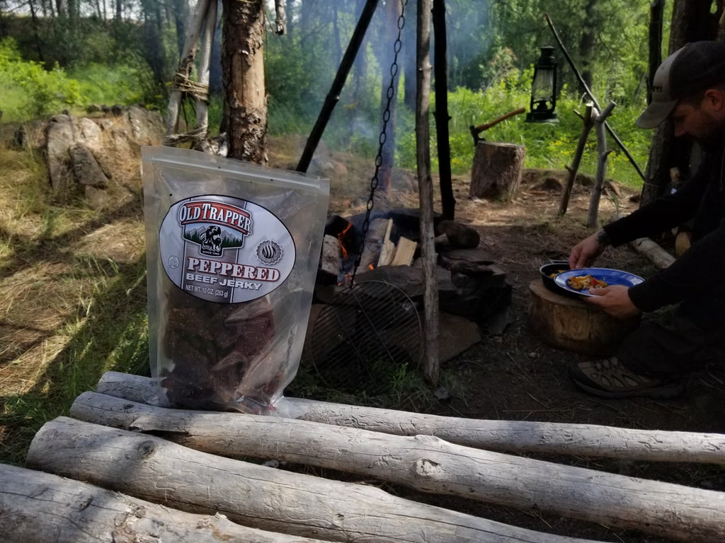Peppered Beef Jerky next to logs and a campfire.