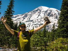 Man holding a bag of Old Trapper Beef Jerky in front of Mt Ranier