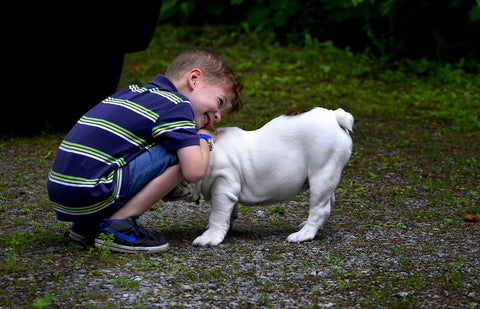 A kid smiling while hugging a dog.