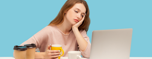 疲惫的女人坐在手提电脑前端着咖啡